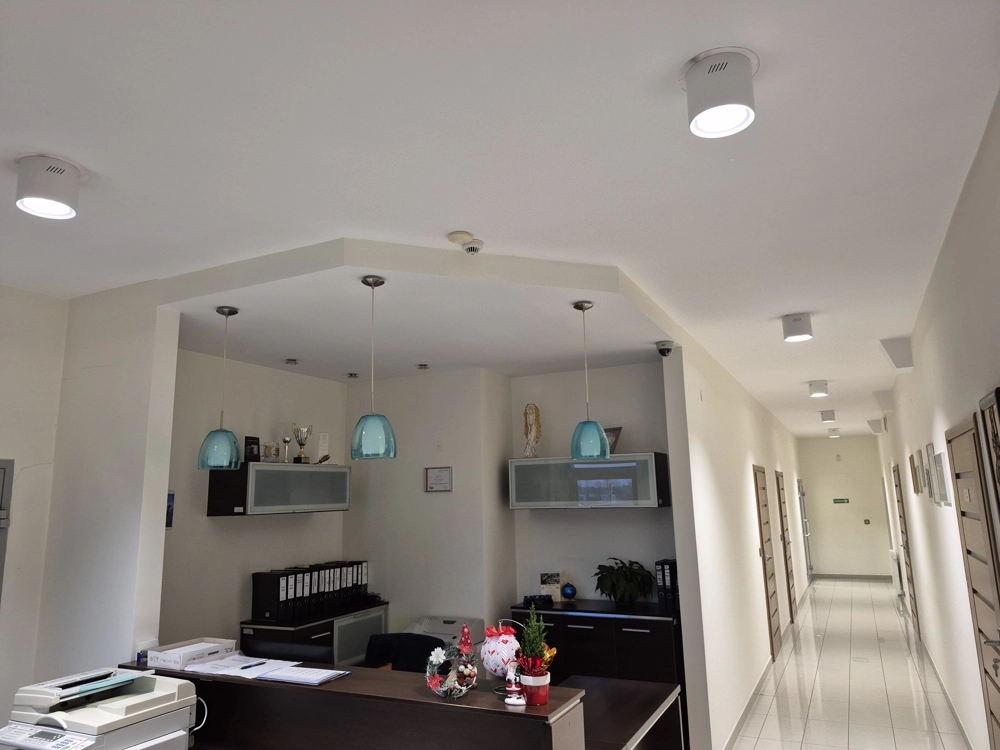 Korytarz i recepcja z sufitowymi oprawami LED i lampami wiszącymi, oświetlenie biurowe
