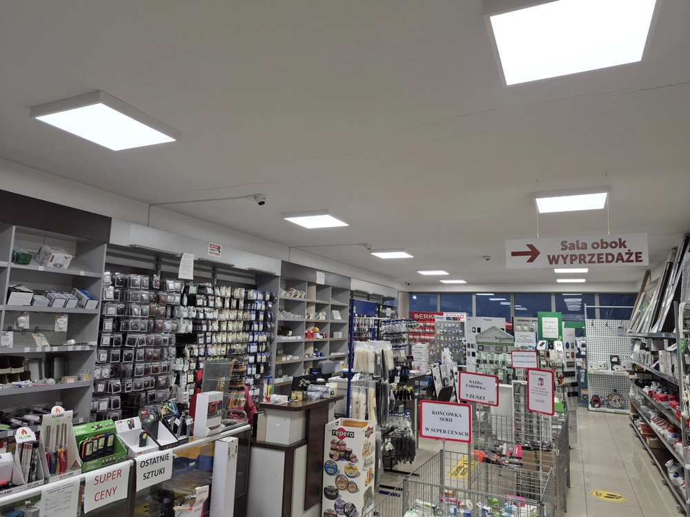 Oświetlenie sklepu jasnymi panelami LED w przestronnym wnętrzu z regałami akcesoriów elektrycznych