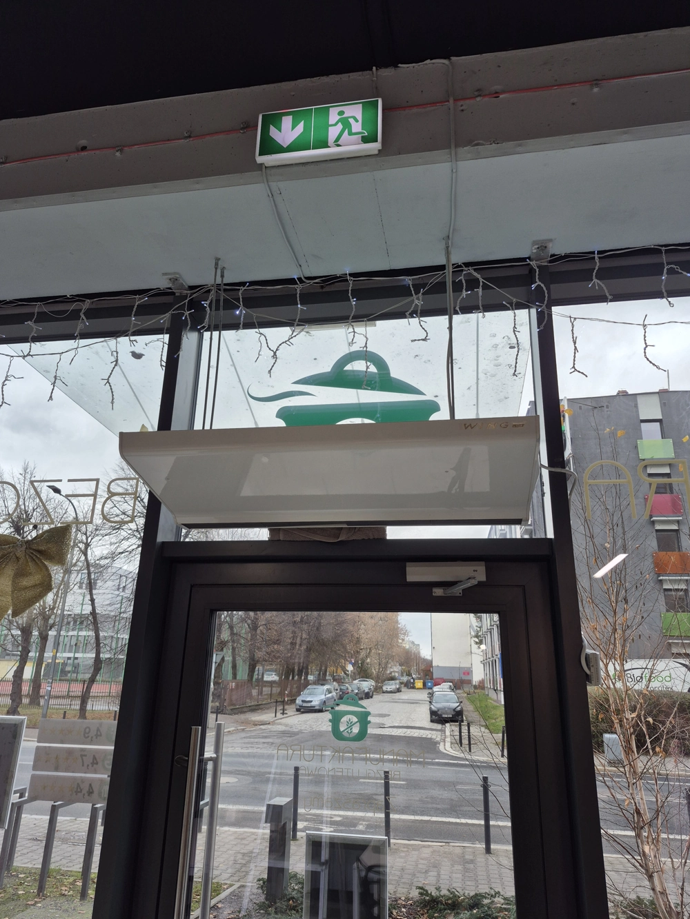 Oświetlenie ewakuacyjne LED zamontowane nad przeszklonymi drzwiami wejściowymi