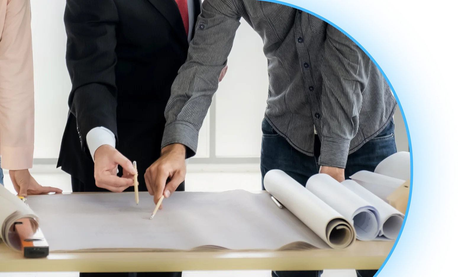 Dwie osoby omawiają projekt Dialux na rozłożonym planie technicznym