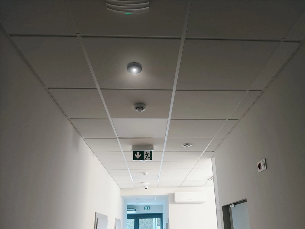 Montaż oświetlenia: korytarz z sufitowymi oprawami LED i oświetleniem ewakuacyjnym
