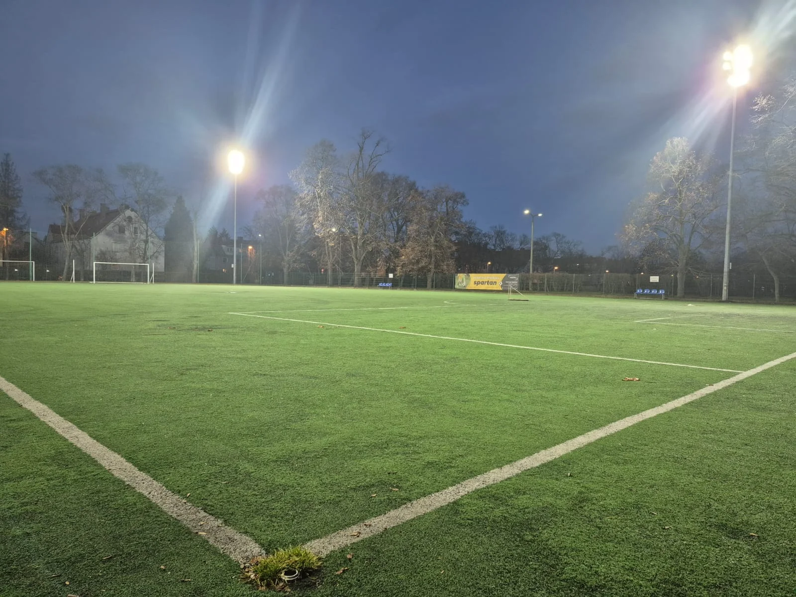 Widok pustego boiska piłkarskiego z sztuczną trawą oświetlonego reflektorami LED (oświetlenie obiektów sportowych)