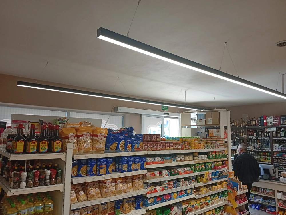 Zawieszone liniowe oprawy LED oświetlają półki sklepu spożywczego, oświetlenie sklepu