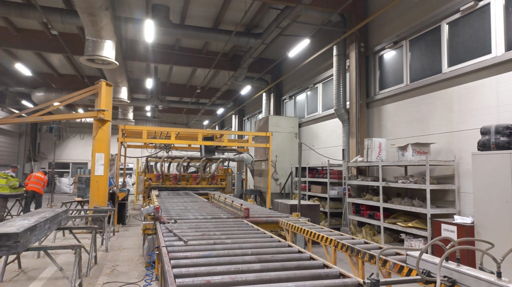Montaż oświetlenia w hali produkcyjnej z rolkowym przenośnikiem i sufitowymi oprawami LED
