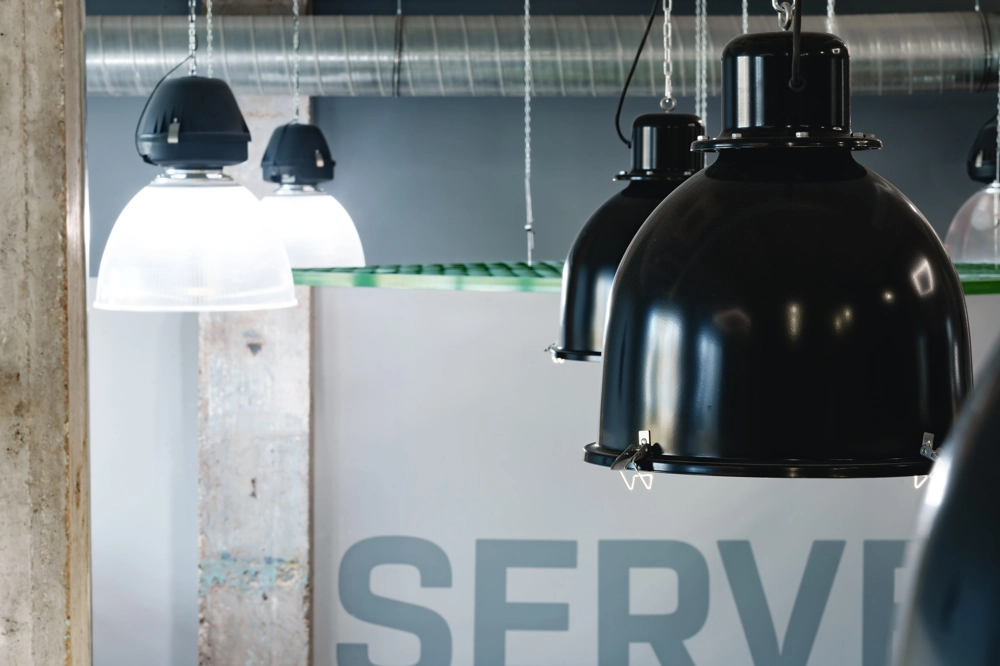 Zawieszone czarne i białe lampy przemysłowe LED nad otwartą halą produkcyjną