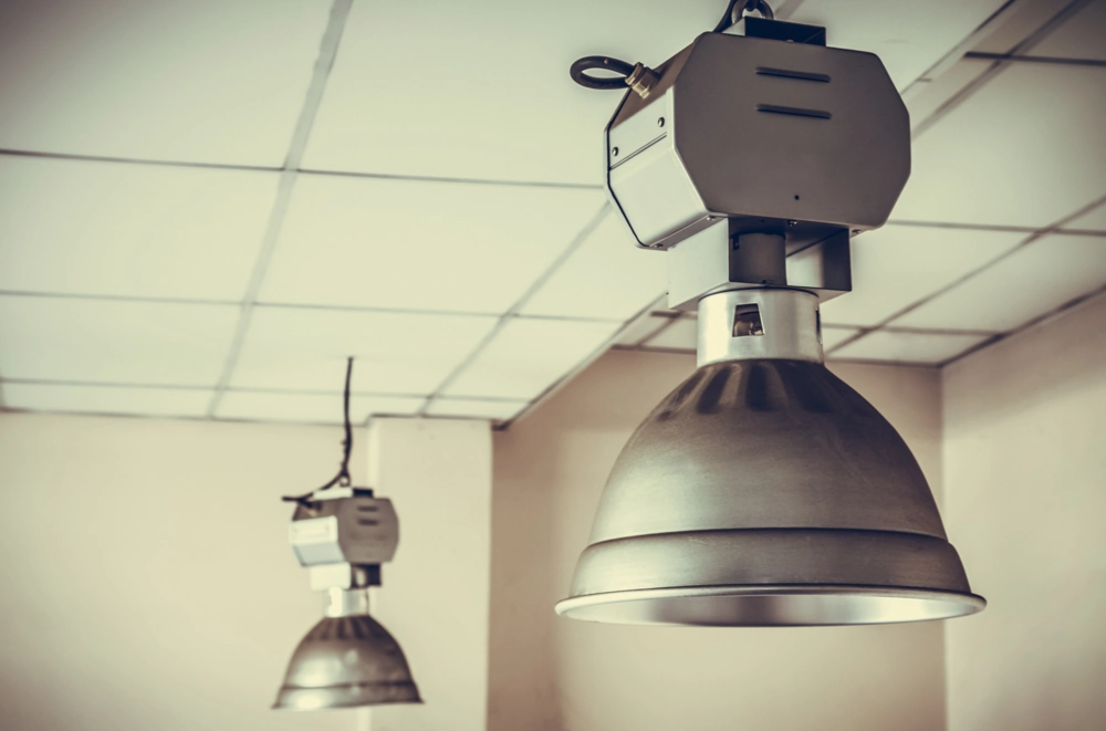 Wiszące metalowe lampy przemysłowe w pomieszczeniu z podwieszanym sufitem