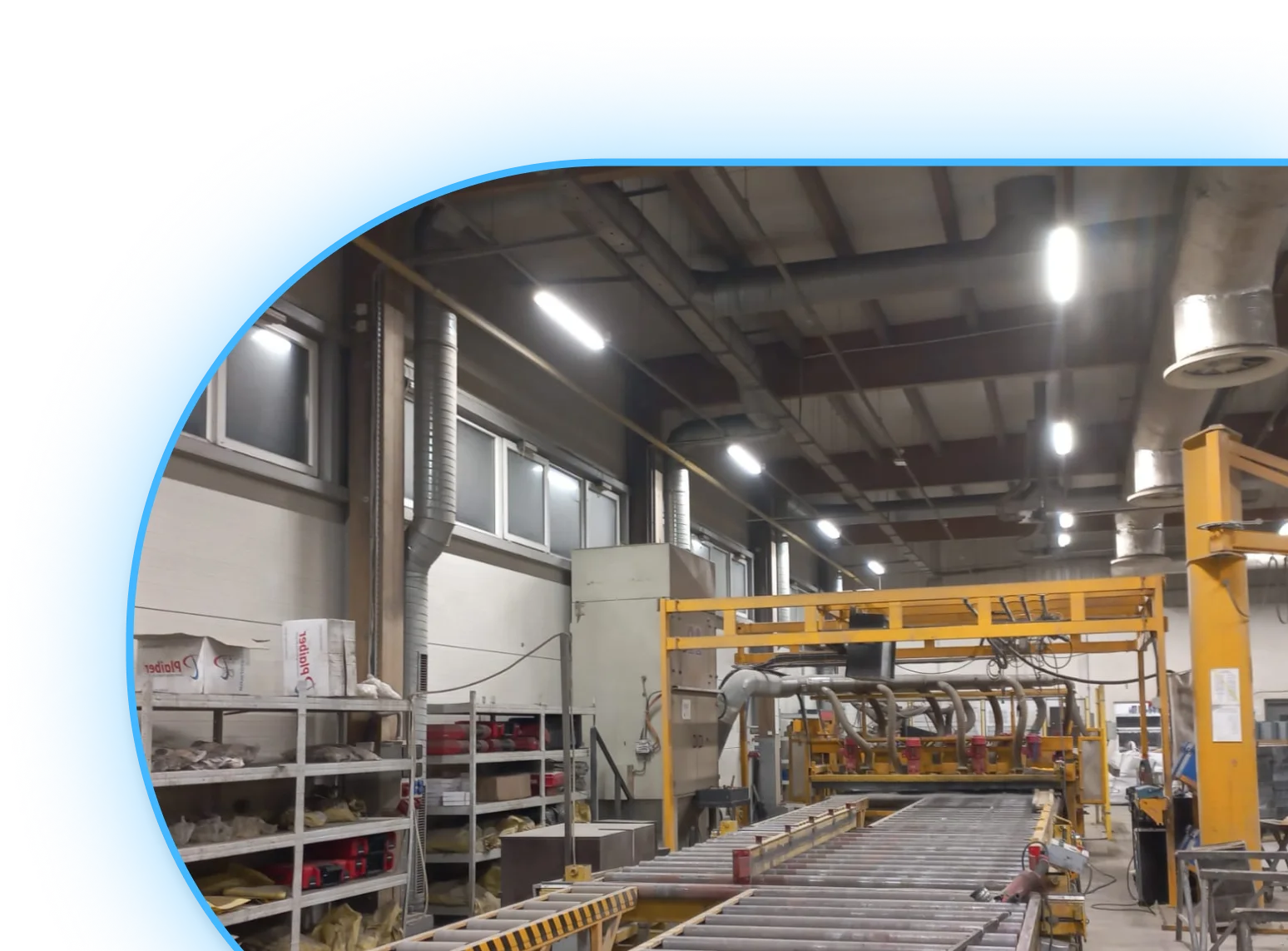 Wnętrze hali produkcyjnej z linią przenośników, na suficie zamontowano lampy do hali produkcyjnej