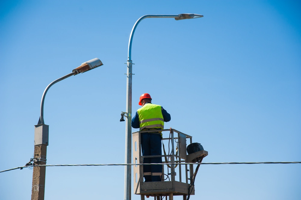 Technik na podnośniku wykonuje montaż oświetlenia ulicznego