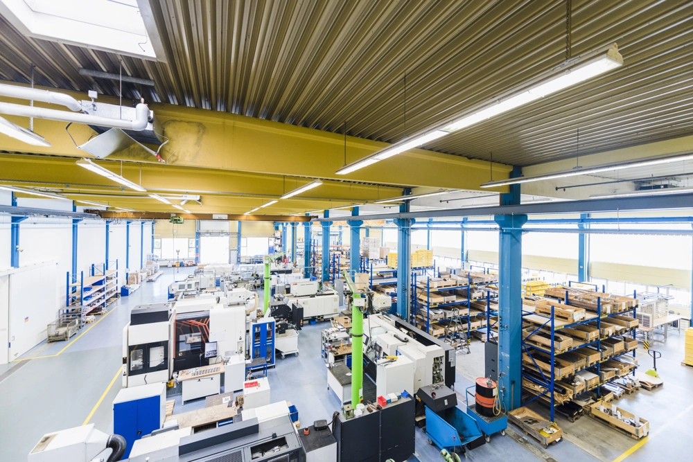 Wnętrze hali produkcyjnej z maszynami i regałami oświetlone lampami do hali produkcyjnej