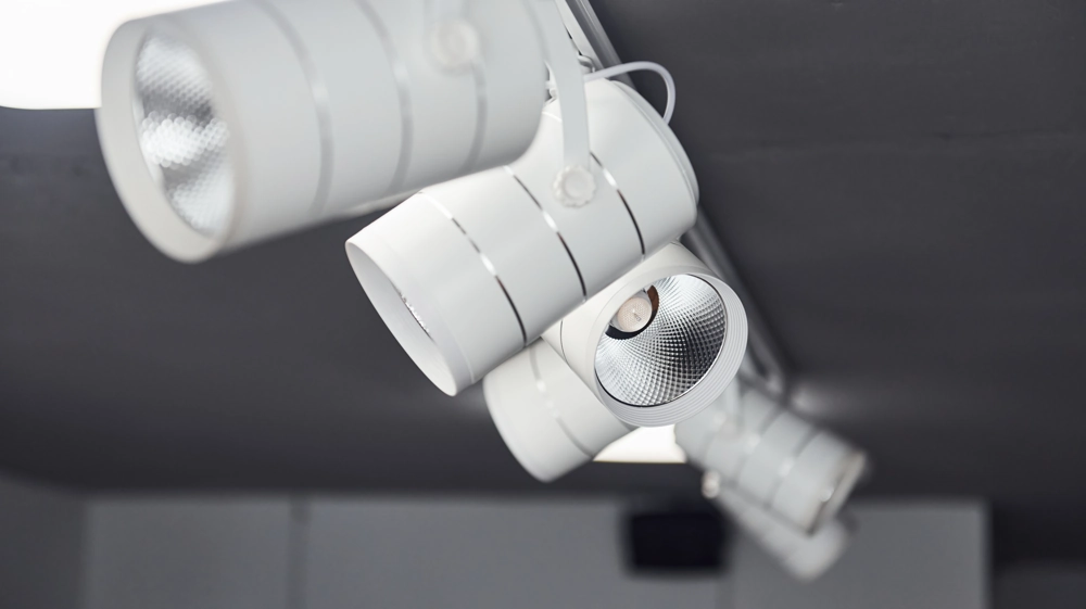 Reflektory LED zamontowane na szynie sufitowej w jasnym wnętrzu – oświetlenie szynowe