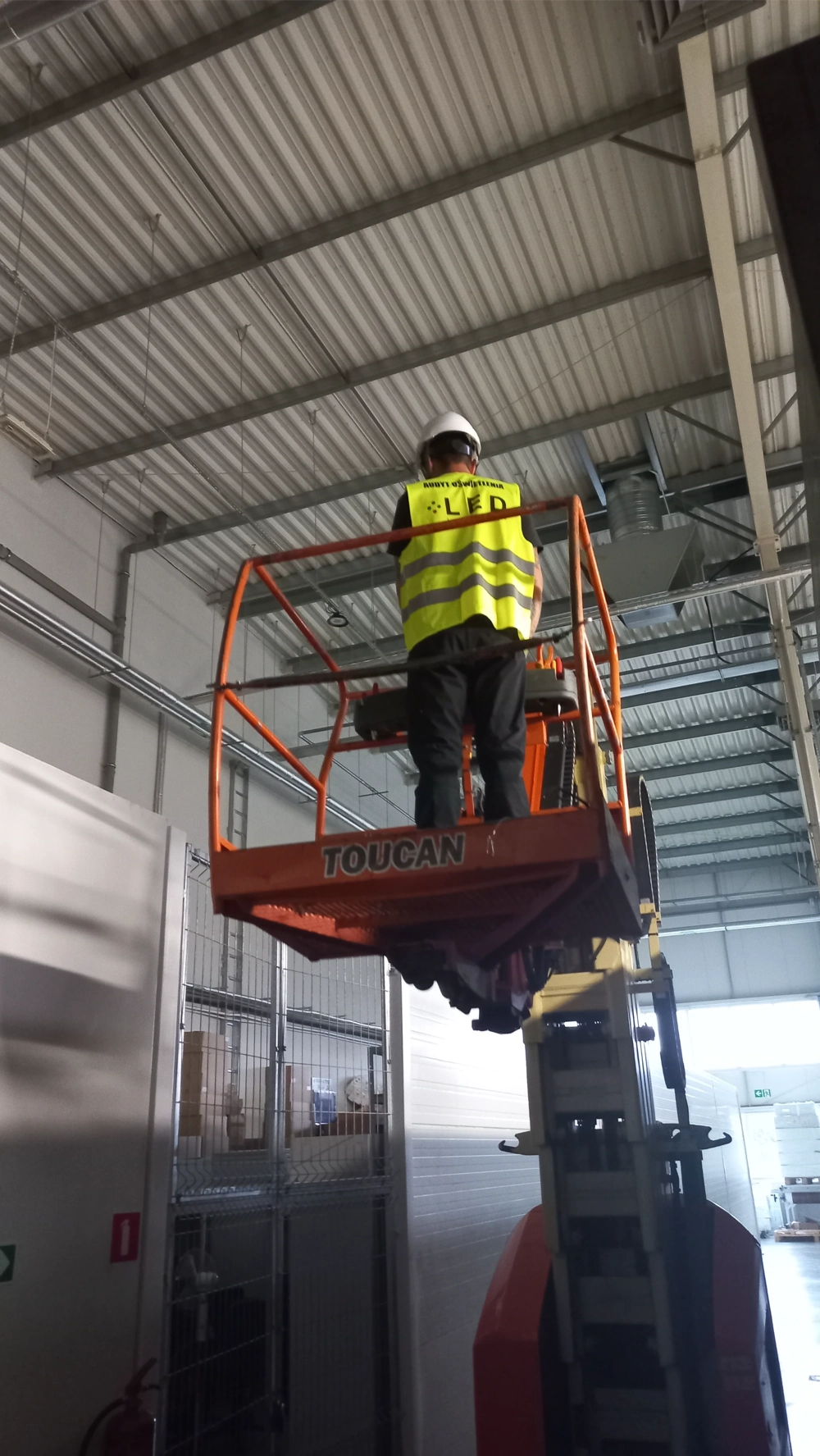 Montaż oświetlenia LED w hali magazynowej przy użyciu podnośnika