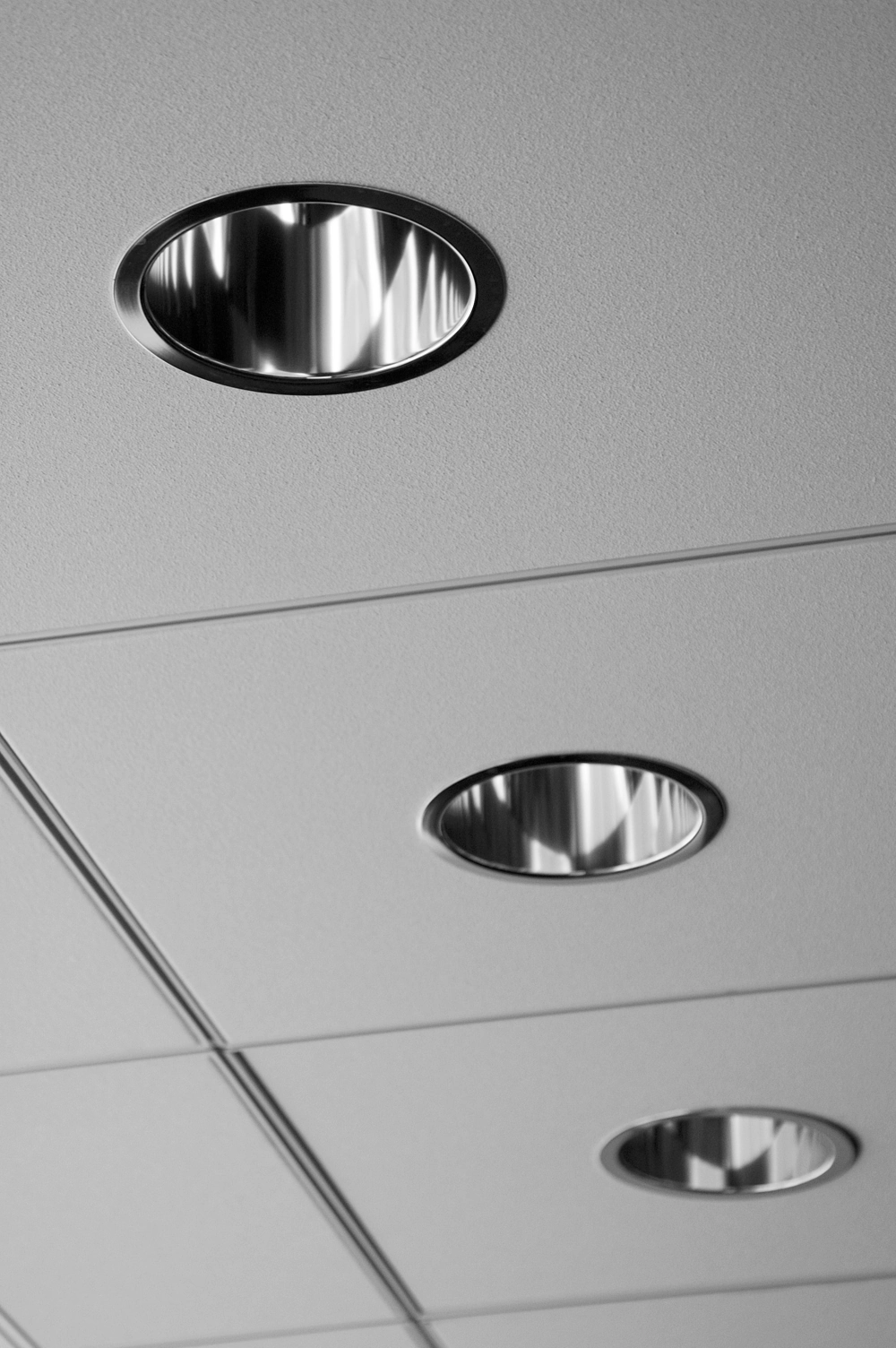 Trzy wpuszczane oprawy oświetleniowe LED w sufit podwieszany o jednolitej fakturze