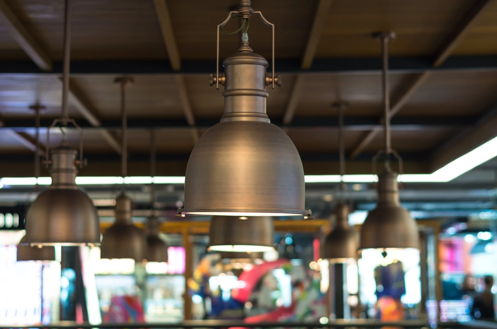 Metalowe oprawy oświetleniowe LED wiszące na sufitowych szynach w przestrzeni handlowej