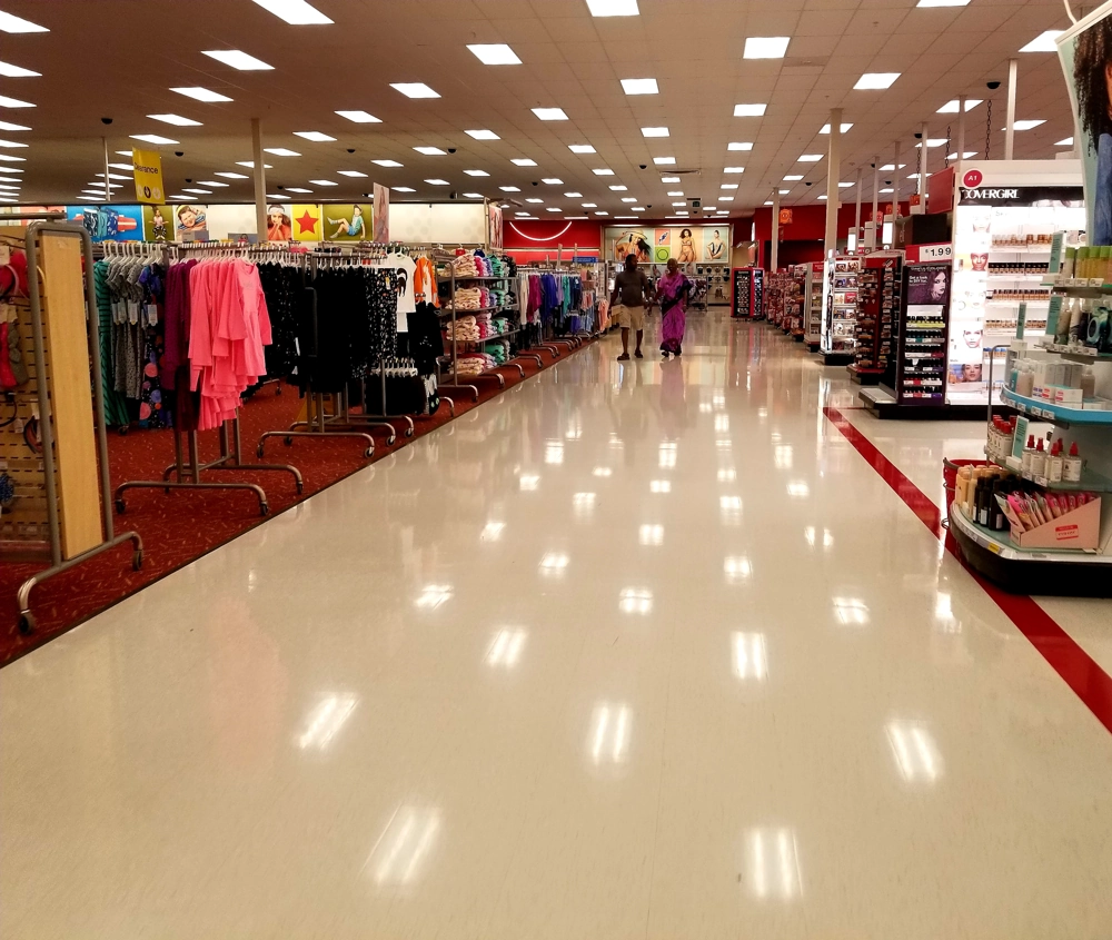 Jasno oświetlony sklepowy korytarz z regałami odzieżowymi i kosmetykami – przykład oświetlenia sklepu