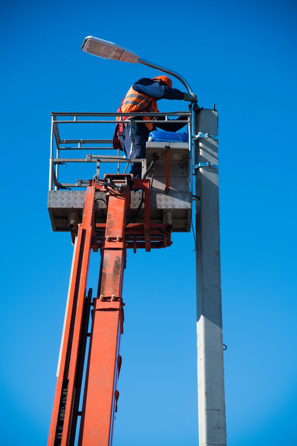 Montaż oświetlenia pracownik na podnośniku instaluje lampę uliczną LED na słupie